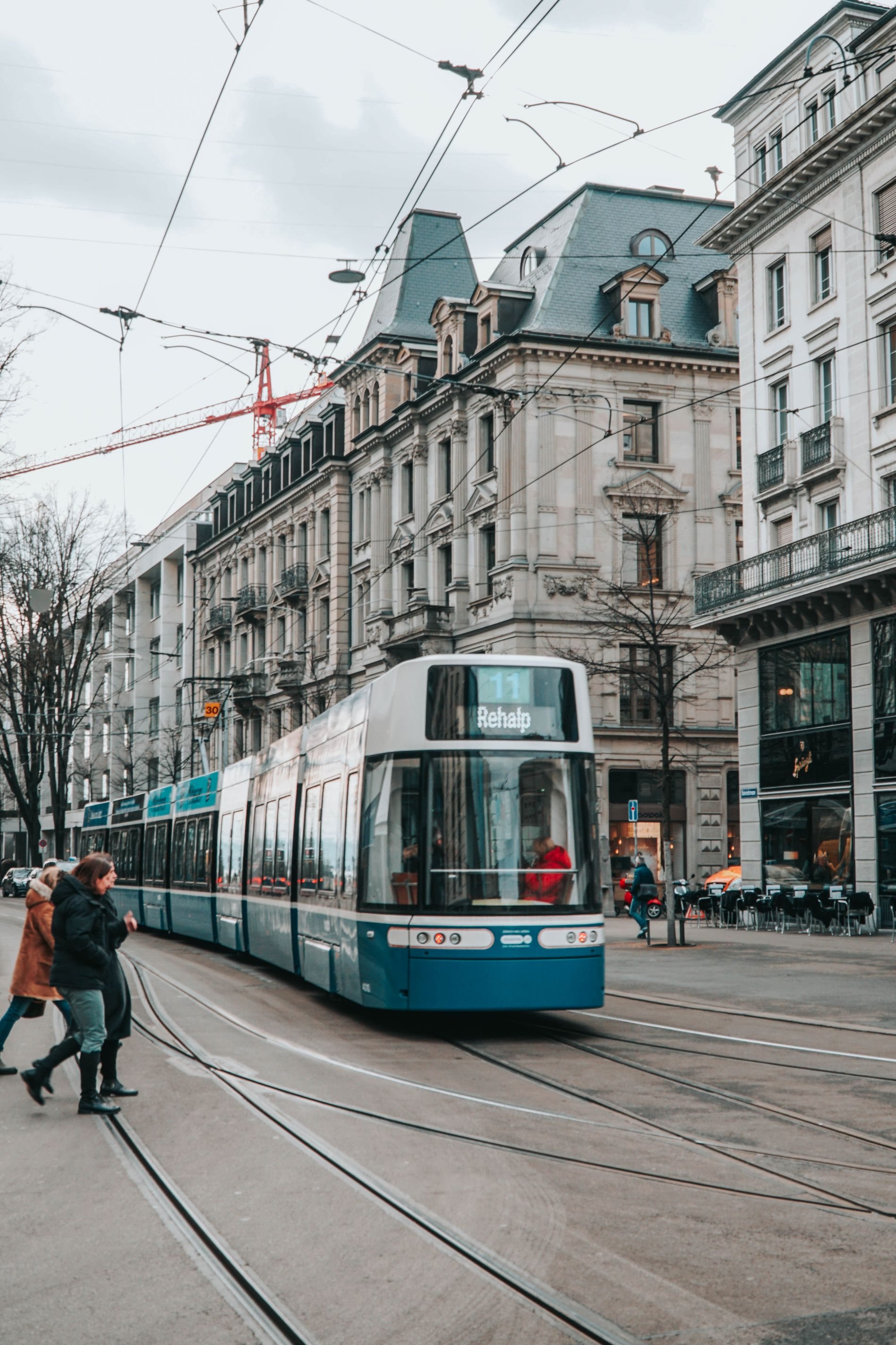 A tram crossing a Zurich street between stone facades